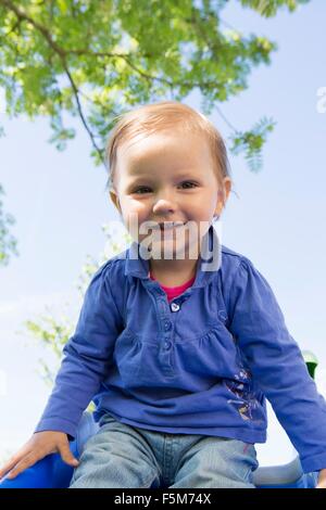 Ritratto di donna bambino seduto sulla parte superiore della diapositiva da giardino Foto Stock