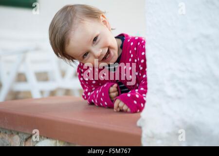 Ritratto di donna toddler sporgersi in avanti e spiata da tabella Foto Stock