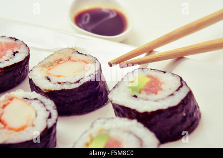 Primo piano di un vassoio con alcune diverse makizushi, riempito con avocado e gamberetti, o di tonno e carne di granchio Foto Stock