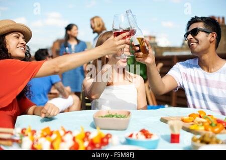 Maschio e femmina amici facendo un brindisi al barbecue sul tetto Foto Stock