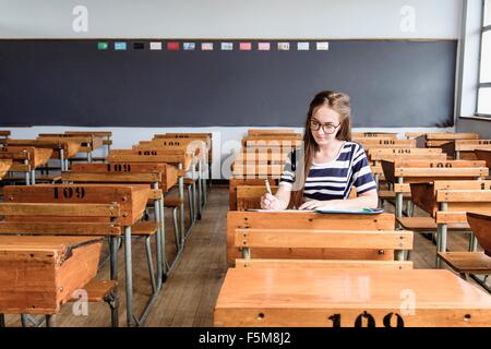 Femmina di lavoro dello studente in aula vuota Foto Stock