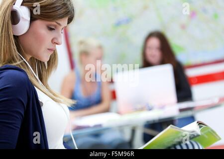Giovane donna che indossa le cuffie, studiare Foto Stock
