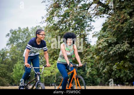 La madre e il figlio a cavallo su biciclette sorridente Foto Stock