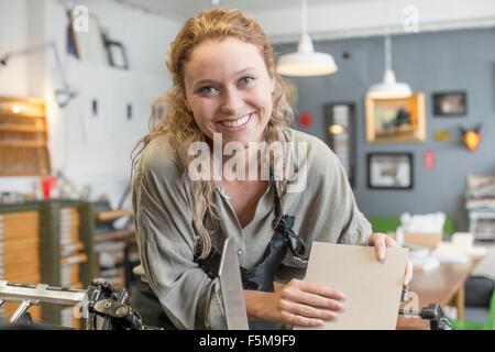 Stampante femmina inserendo carta per macchina da stampa in officina Foto Stock