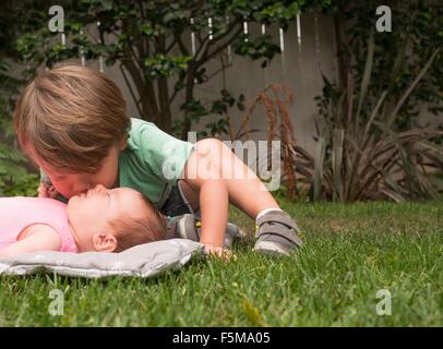 Ragazzo, kissing baby sorella, all'aperto Foto Stock