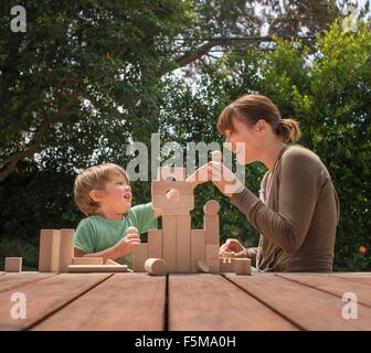 Madre e figlio giocare con costruzione in legno blocchi in giardino Foto Stock