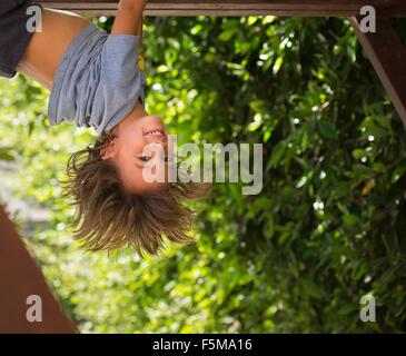 Giovane ragazzo appeso a testa in giù Foto Stock