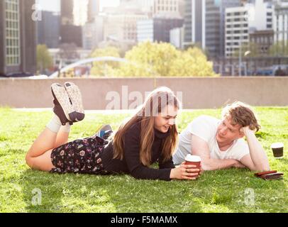Coppia giovane avente pausa caffè su erba, Melbourne, Victoria, Australia Foto Stock