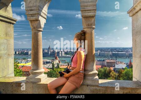 Metà donna adulta guardando alla vista di Buda dal Bastione del Pescatore, Budapest, Ungheria Foto Stock