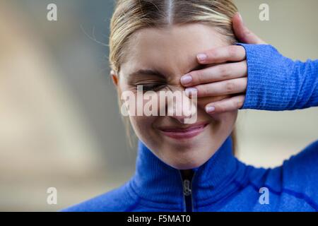 Giovane donna strizzare gli occhi a disagio nell'occhio Foto Stock
