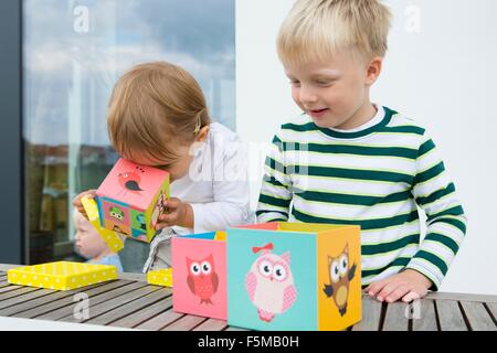 Ragazzo e toddler femmina giocando con il gufo di blocchi di costruzione sul patio Foto Stock
