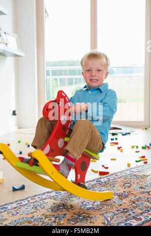 Ritratto di ragazzo giocando sul cavallo a dondolo Foto Stock