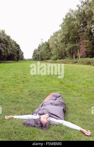 Senior donna dentro il sacco a pelo, in campo, braccia tese Foto Stock