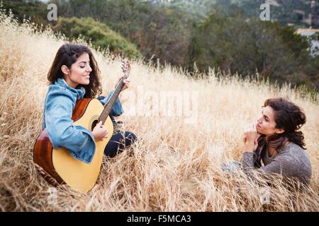 Giovane donna in erba lunga a suonare la chitarra ad un amico, Woodland Hills, in California, Stati Uniti d'America Foto Stock