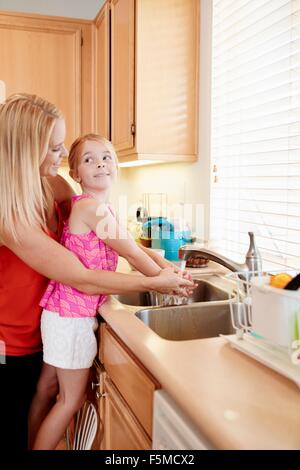 Madre figlia di lavaggio le mani nel lavello da cucina Foto Stock