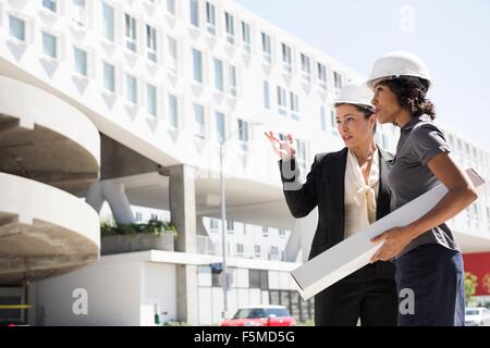 Due imprenditrici, indossare copricapi rigidi, i piani di trasporto Foto Stock