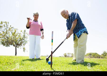 Coppia senior giocando croquet, all'aperto Foto Stock