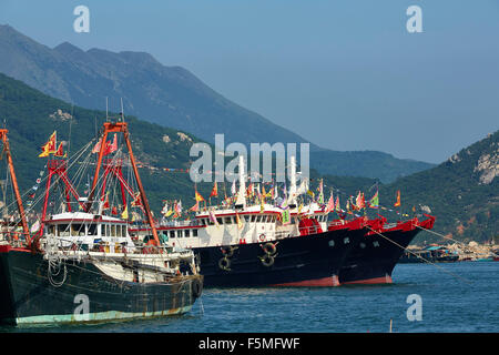 Commerciale di pesca barche ormeggiate in Cheung Chau porto, le montagne dell'Isola di Lantau in background dietro, Hong Kong. Foto Stock