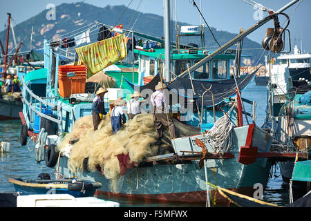 Equipaggio riparare reti su un Commerciale di pesca barca ormeggiata in Cheung Chau, Porto di Hong Kong. Foto Stock