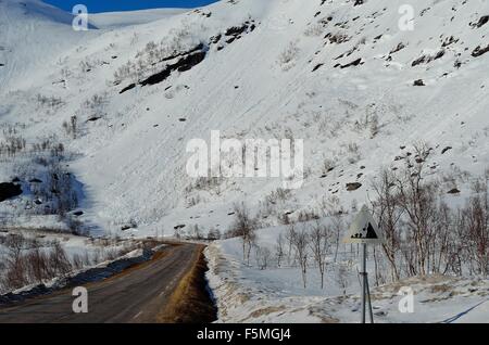 La caduta di roccia segno di pericolo di fronte a una coperta di neve montagna sulla sommità del Kaperdalen, Norvegia Foto Stock