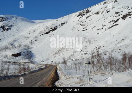 La caduta di roccia segno di pericolo di fronte a una coperta di neve montagna sulla sommità del Kaperdalen, Norvegia Foto Stock