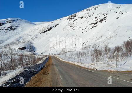 La caduta di roccia segno di pericolo di fronte a una coperta di neve montagna sulla sommità del Kaperdalen, Norvegia Foto Stock