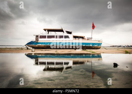 Una bella immagine di un fatiscente barca catamarano riflessa nel mare dell'isola indonesiana di Bali. Una cruda immagine di un età compresa tra nave passeggeri. Foto Stock