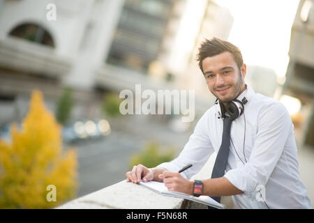 Imprenditore prendendo appunti su un notebook in città Foto Stock