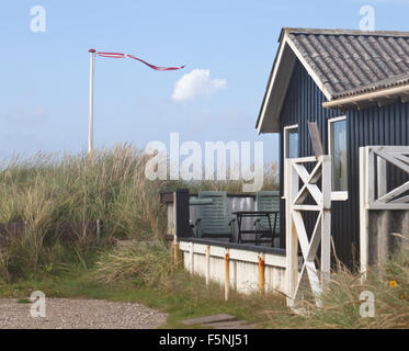 Una casa estiva completo con una bandiera danese si annida nelle dune di sabbia accanto alla spiaggia. Foto Stock