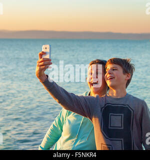 Ragazzo e una felice donna adulta prendendo un selfie davanti a un lago il ragazzo ha rinforzi su i suoi denti Foto Stock