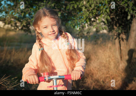 Bella ragazza scooter di guida su strada rurale outdoor in natura Foto Stock