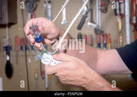 Il fissaggio di un indossava di messa a terra alla presa elettrica Foto Stock