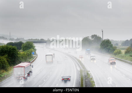 I veicoli che utilizzano una trafficata autostrada M5 in Somerset durante una tempesta di pioggia con un sacco di spruzzo rendendo la visibilità scarsa e molto difficili le condizioni di guida Foto Stock