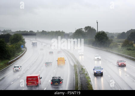 I veicoli che utilizzano una trafficata autostrada M5 in Somerset durante una tempesta di pioggia con un sacco di spruzzo rendendo la visibilità scarsa e molto difficili le condizioni di guida Foto Stock