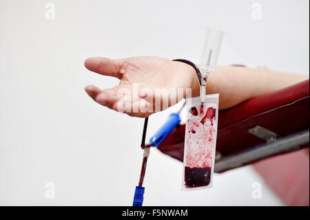 Dettaglio con la mano di un donatore di sangue e una plastica sacca di sangue in un ospedale Foto Stock