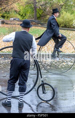 Uomo che corre in bicicletta con un abito d'epoca tradizionale, gara di Penny Farthing Bicycle City. Praga indossa, cappotto coda, cappotto posteriore Foto Stock