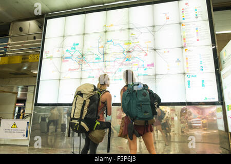 Due giovani, femmina, femmine,donne,zaini, backpackers, cercando, in,e, treno,metro,mappa della metropolitana presso la stazione ferroviaria di Sants,Barcellona,Cataluña,Spagna, Foto Stock