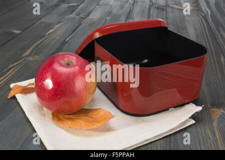 Red apple e una scatola aperta per la scuola prima colazione sul buio superficie in legno Foto Stock