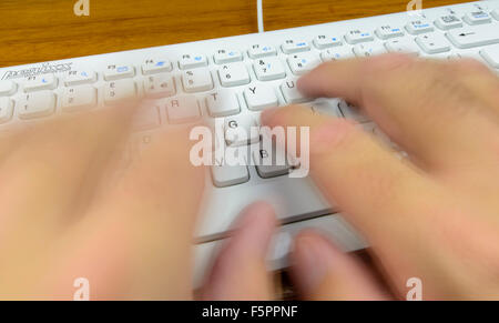 La digitazione rapida sulla tastiera di un computer con il dattilografi mani sfocato per dedurre la velocità. Foto Stock