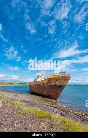 Una lavata fino abbandonato rusty barca ad alta marea su una giornata d'estate Foto Stock