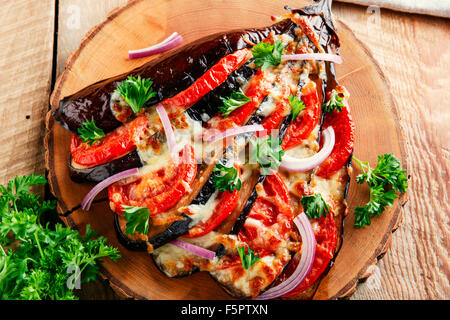 Melanzane al forno con formaggio e pomodoro su una superficie in legno Foto Stock