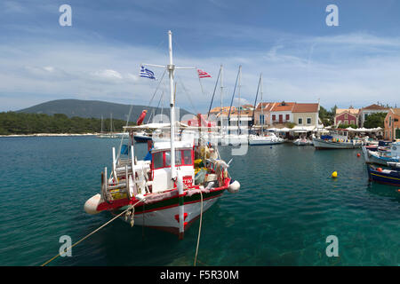 Un greco barca da pesca e yatchs sono ormeggiati nel pittoresco villaggio di Fiskardo, Cefalonia, Grecia Foto Stock