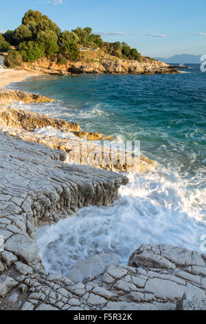 La roccia Bataria e Kanoni beach, Kassiopi Corfù sono accesi con la forte luce arancione di sunrise. Foto Stock