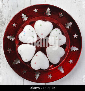 Decorazione di natale - piastra di rosso e bianco cuori su sfondo di legno Foto Stock