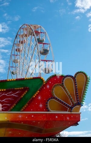 Una ruota panoramica Ferris torreggia sopra un lato in stallo in un luna park su Blackpools Molo Centrale Foto Stock