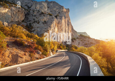 Strada asfaltata nel bosco in autunno a sunrise. Montagne di Crimea. Foto Stock