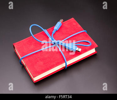 Blue Ribbon dal cavo usb sul libro come un presente Foto Stock