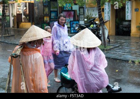 Hoi An old town in Vietnam. Stagione umida e piogge pesanti in città. Vietnamese street food signore con la bicicletta e occidentali Foto Stock