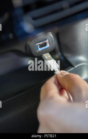 Stretta di mano che trattiene il connettore USB in auto Foto Stock