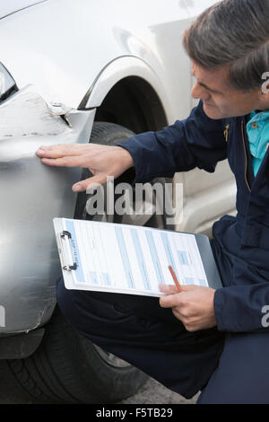 Auto Officina Meccanica di ispezionare i danni alla vettura e Riempimento nella stima di riparazione Foto Stock